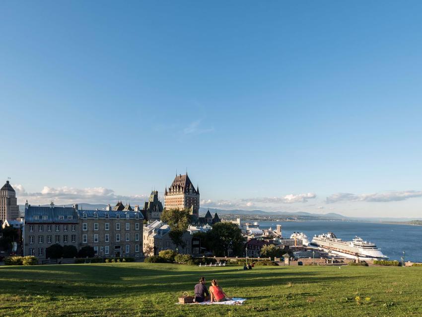 Pique-nique en couple près de la terrasse Pierre-Dugas-De Mons, devant un panorama du Vieux-Québec et du fleuve Saint-Laurent.